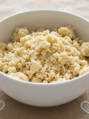 Ciotola bianca con impasto di pasta frolla impazzita e sbriciolata su una tovaglia beige con cuori