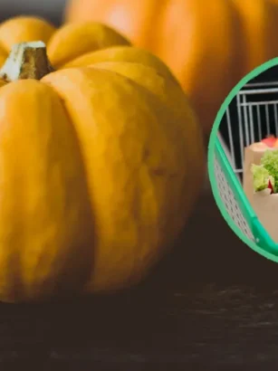 Primo piano di una zucca intera arancione su piano scuro con riquadro che mostra un carrello della spesa con buste di ortaggi.