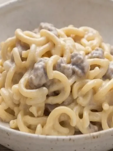 Piatto di gramigna con salsiccia e fonduta di gorgonzola cremosa servito in una ciotola rustica su tavolo in legno