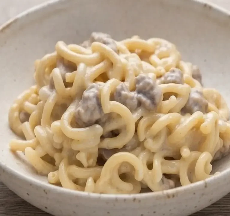 Piatto di gramigna con salsiccia e fonduta di gorgonzola cremosa servito in una ciotola rustica su tavolo in legno