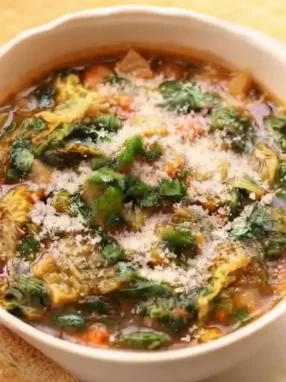 Ciotola di ceramica con minestrone autunnale brucia grassi e drenante a base di verdure di stagione, verza e zucca.