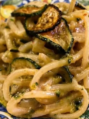 Piatto di Pasta alla Nerano originale mantecata con zucchine fritte e provolone su piatto di ceramica decorato