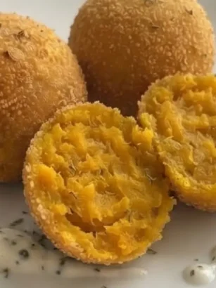 Polpette di zucca e ricotta su un piatto cn tovaglia azzurra sullo sfondo
