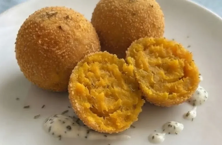 Polpette di zucca e ricotta su un piatto cn tovaglia azzurra sullo sfondo