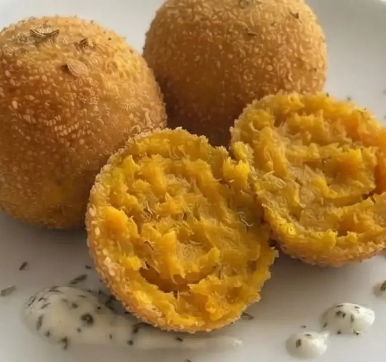 Polpette di zucca e ricotta su un piatto cn tovaglia azzurra sullo sfondo