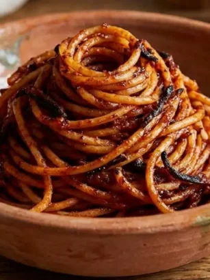 Piatto in terracotta con un nido di spaghetti all'assassina rossi, piccanti e con la tipica crosticina bruciacchiata